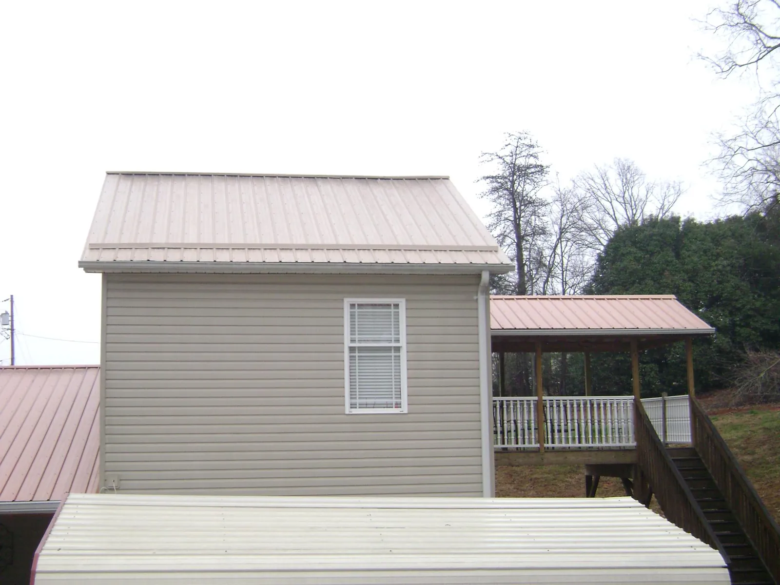 Tan metal roofs on a two story addition and attached porch, from a Roof Replacement job in Denver